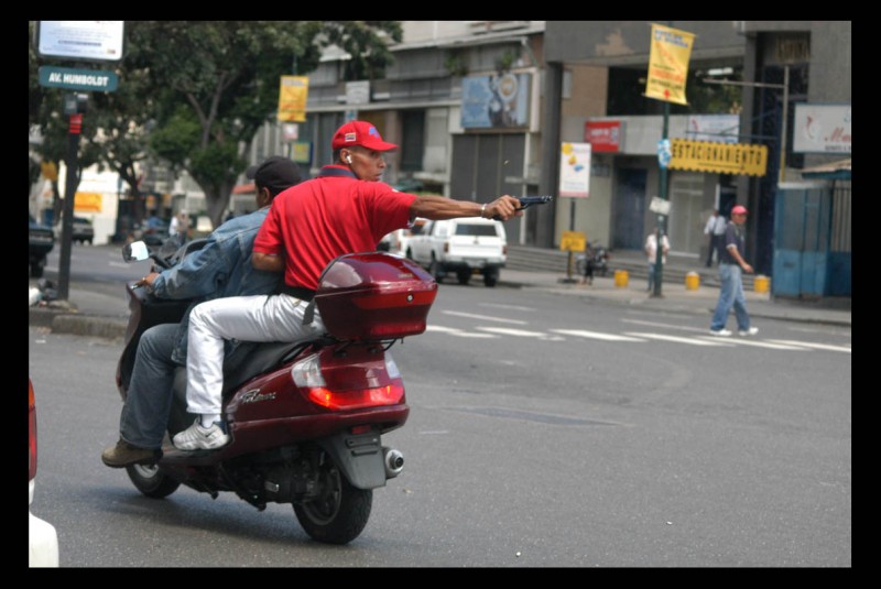 Un efectivo policial dispara su arma de reglamento contra un grupo de manifestantes adversos al presidente venezolano Hugo Chávez.  El hecho ocurrió en la avenida Casanova, de Caracas, capital venezolana.
